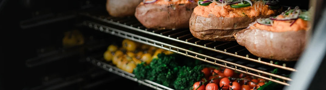 Baked sweet potatoes topped with fresh herbs and other vegetables on the warming racks of a Gravity Series grill