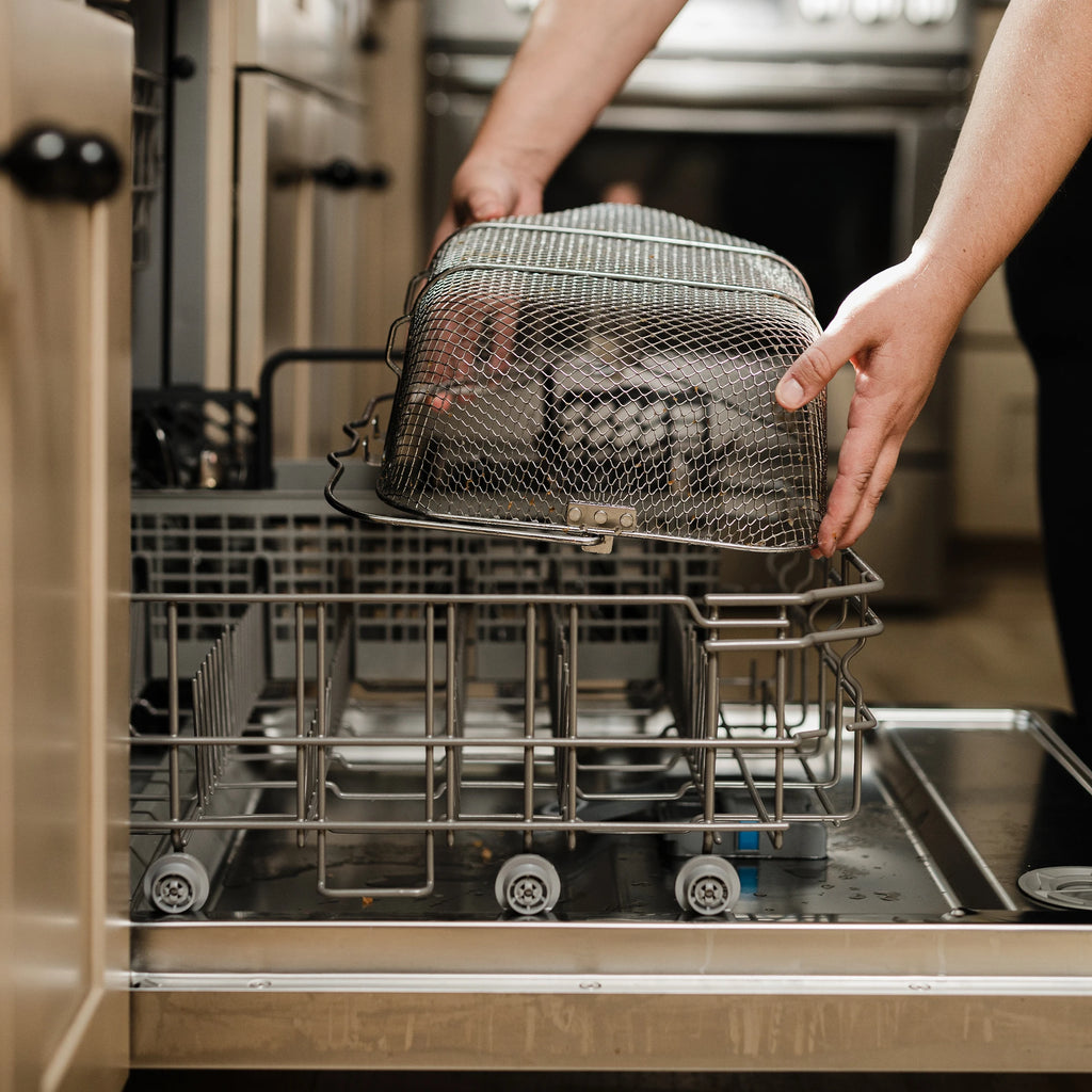 Putting the dishwasher-safe basket into the lower rack of a dishwasher for easy cleanup.