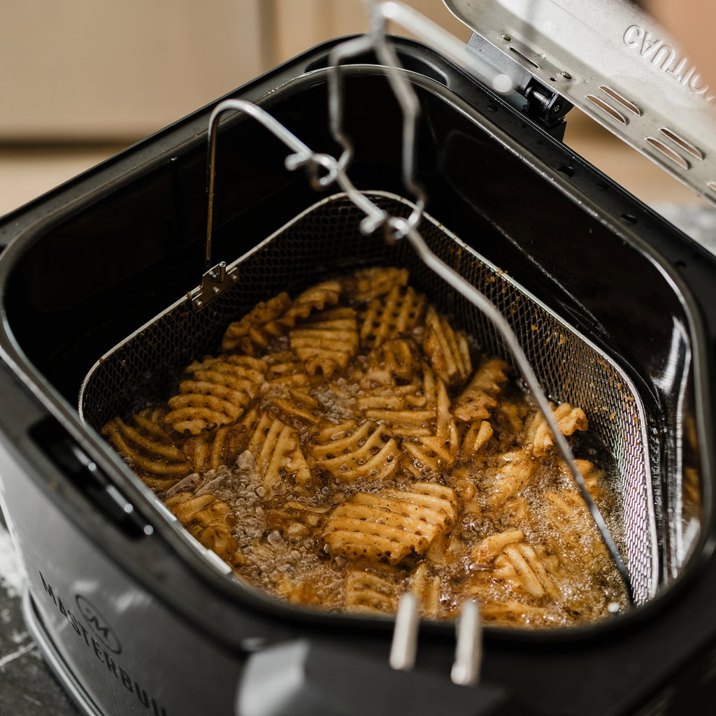 Waffle fried cook in the fryer. The basket bailing wire is up and attached to a 2-prong hook for easy removal.