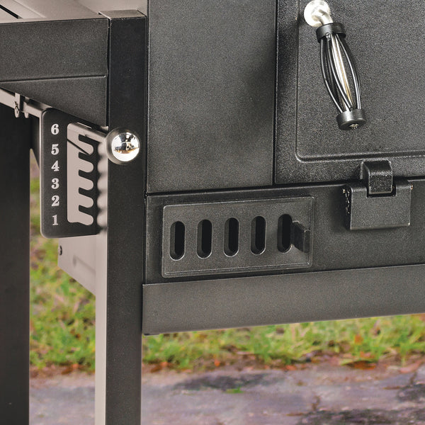 Closeup of the 6-setting grill grate adjustment control knob on the left side of the grill body. The left adjustable air flow vent and the left handle of the charcoal access door are also visible.