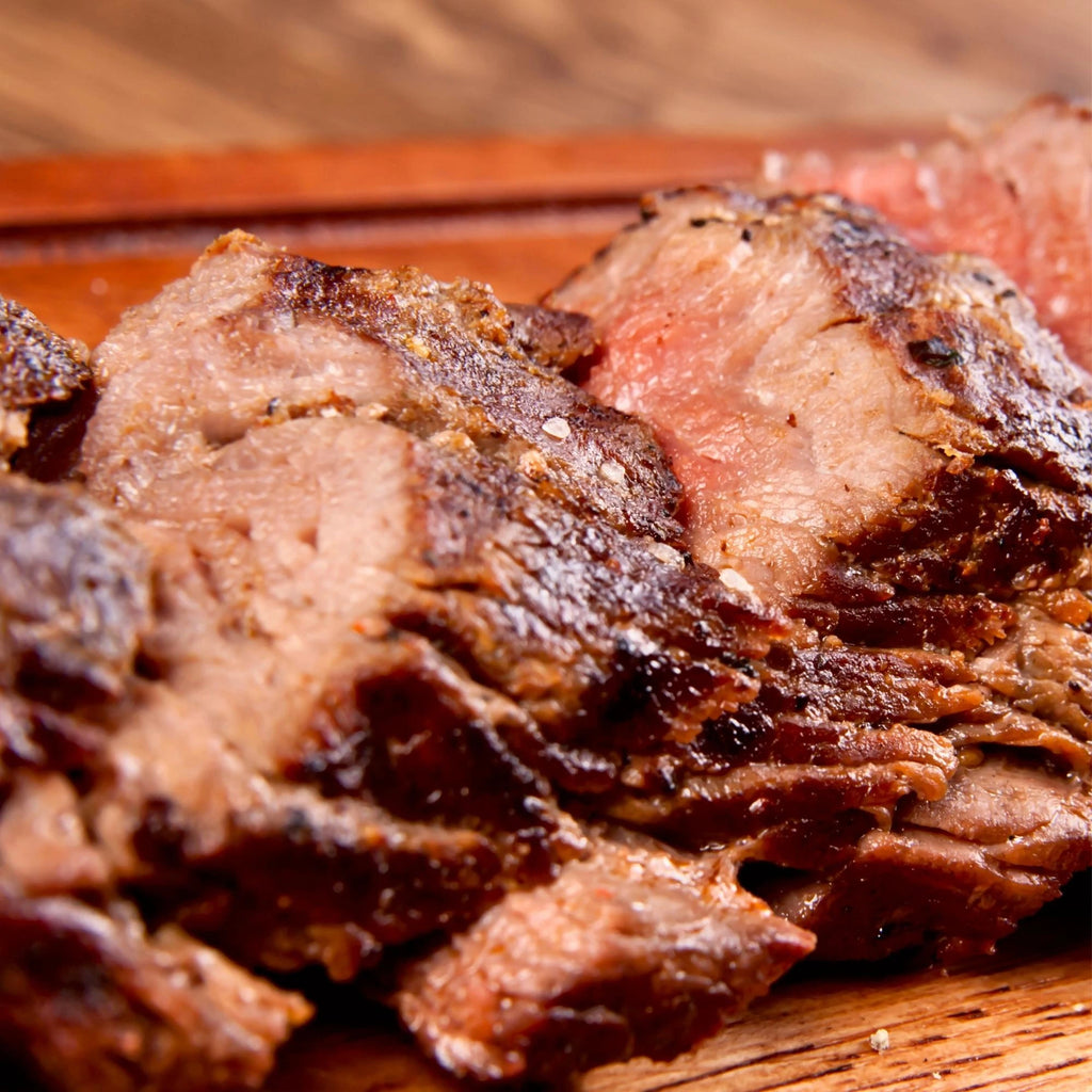 A sliced smoked brisket resting on a wooden board, ready for serving.