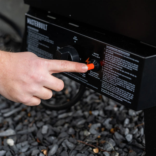 A man presses the orange auto-ignite button on the control panel.