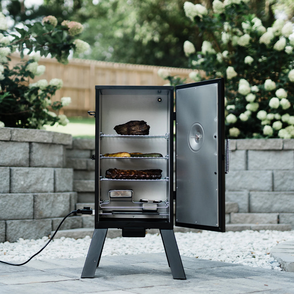 The smoker open to show 3 racks of food sitting above the wood and water trays. The power cord with temperature control knob plugs into the bottom left side of the smoker.