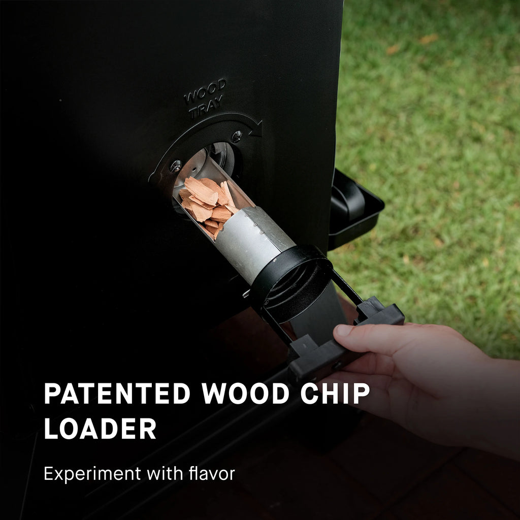 Patented wood chip loader being used on a grill with grass in the background. Use the patented wood chip loader to experiment with flavor.