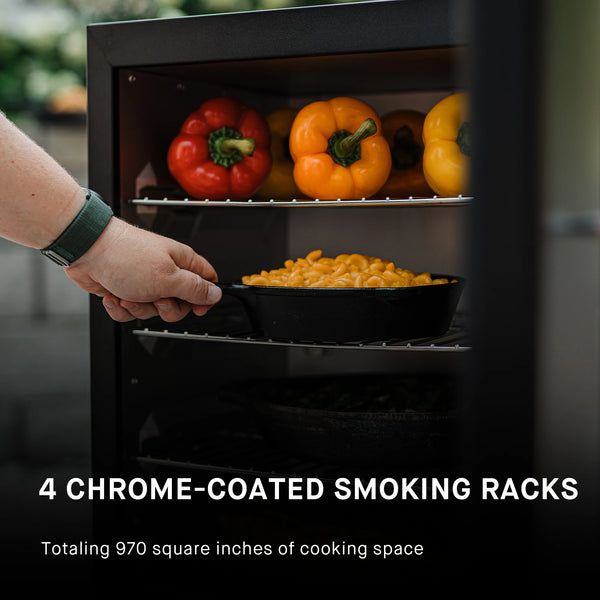 4 chrome-coated smoking racks totaling 970 square inches of cooking space. Shown here from top rack down are racks with: 6 bell peppers, a cast iron skillet of mac and cheese, a cast iron dish full of vegetables, and a whole rack of ribs.