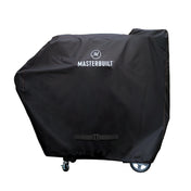 Black cover with orange double-stitching and white Masterbuilt name and logo covers a large Gravity Series Grill + Smoker. Cord with buckle at the bottom keeps the cover secure.