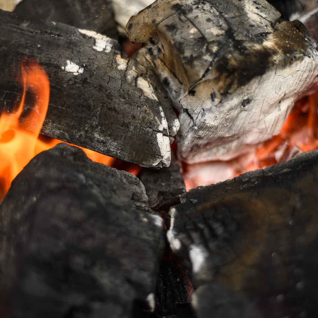 Extreme closeup of burning large lump charcoal on top of a bed of coals