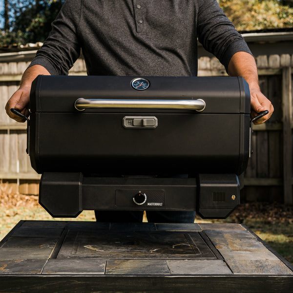 Man lifting a Portable Charcoal Grill with the lid closed and locked