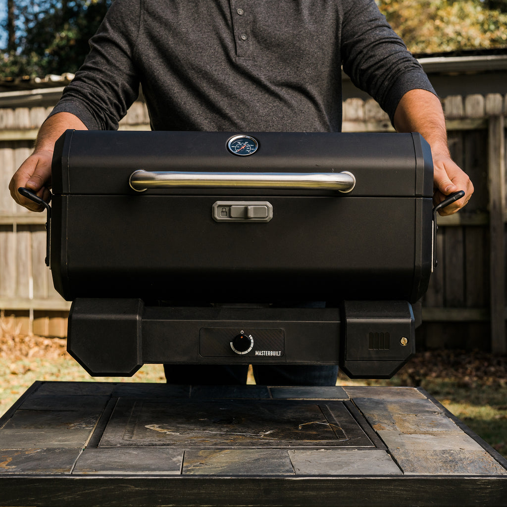 A man lifts a closed and locked Portable Charcoal Grill (without cart)