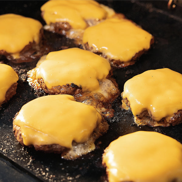 Cheeseburgers sizzle on a griddle